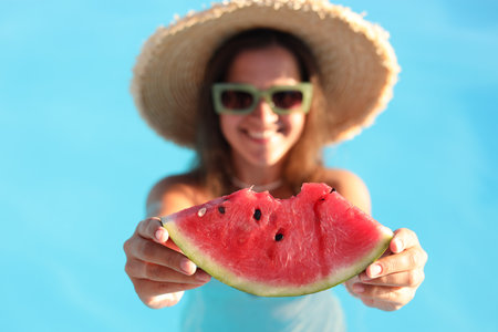 Happy woman with slice of juicy watermelon in swimming pool outdoors, selective focusの写真素材