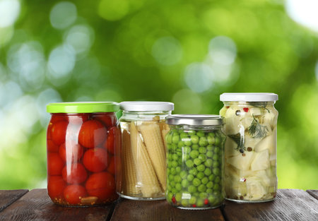 Jars with pickled vegetables on wooden table outdoors, space for textの写真素材