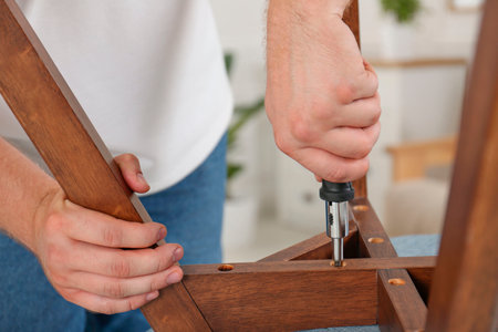 Man with screwdriver assembling furniture indoors, closeupの写真素材