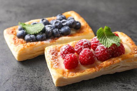 Tasty puff pastries with berries on gray table, closeupの写真素材