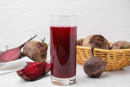 Fresh beet juice in glass and ripe vegetables on white tiled tableの写真素材
