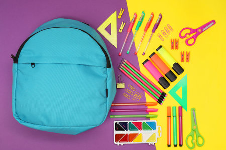 Flat lay composition with backpack and different school stationery on color backgroundの写真素材