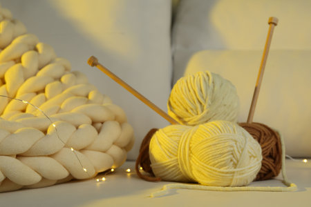 Skeins of yarn, knitting needles and festive lights on sofaの写真素材
