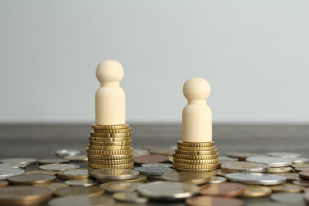 Financial inequality. Human figures and coins on wooden tableの写真素材