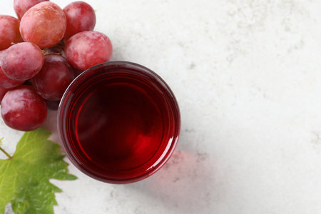 Tasty grape juice in glass, leaf and berries on light table, flat lay. Space for textの写真素材