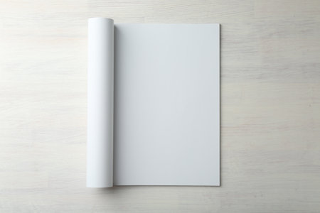 Open magazine with blank page on light wooden table, top view. Mockup for designの写真素材