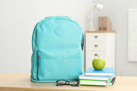 Backpack and different school stationery on wooden table indoorsの写真素材