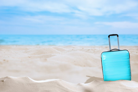 One turquoise suitcase on sandy beach near sea. Space for textの写真素材