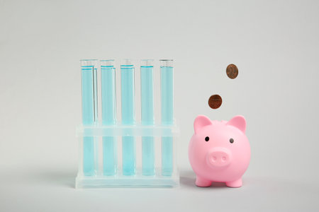 Water save concept. Piggy bank, coins and liquid in test tubes on light blue backgroundの写真素材