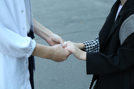 Mother and daughter holding hands outdoors, closeupの写真素材