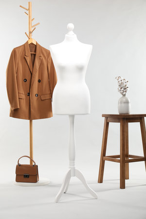 One female mannequin, rack with jacket, stool, cotton flowers and bag on light backgroundの写真素材