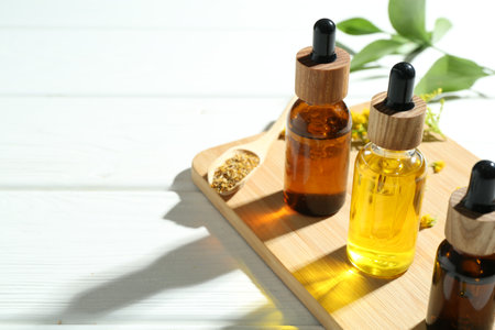 Tinctures in bottles and medicinal herbs on white wooden table, closeup. Space for textの写真素材