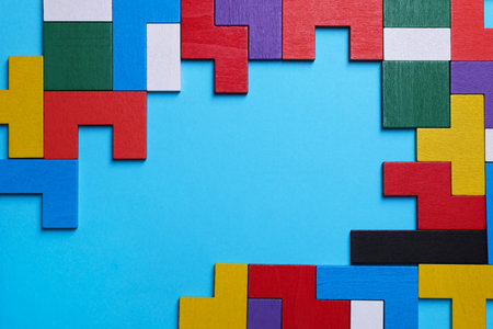 Colorful wooden puzzle pieces on light blue background, top view. Space for textの写真素材