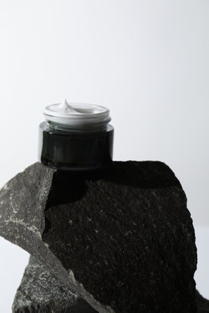 Face cream in jar on stone against light backgroundの写真素材