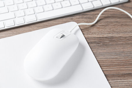 Computer mouse with mousepad and keyboard on wooden desk, closeupの写真素材