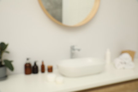 Blurred view of countertop with sink, towels, houseplant and mirror in bathroomの写真素材