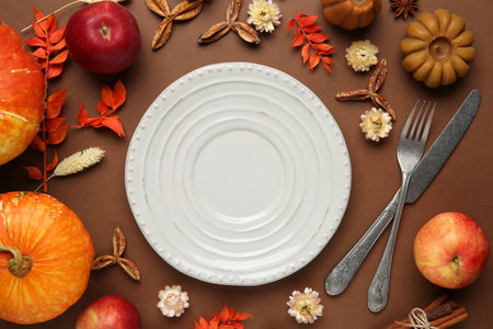 Beautiful table setting with autumn decor on brown background, flat layの写真素材