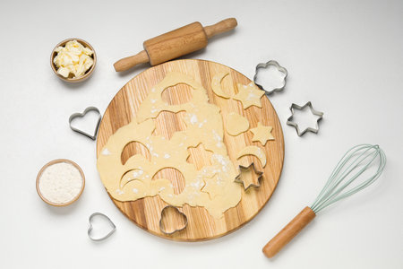 Raw dough, cookie cutters, rolling pin, butter and flour on white table, flat lay