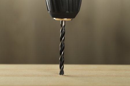 Drilling hole in wooden plank on gray background, closeupの写真素材