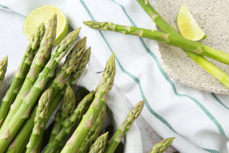 Fresh green asparagus stems and lime on table, flat layの写真素材
