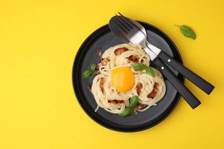 Delicious pasta Carbonara served on yellow table, top view. Space for textの写真素材