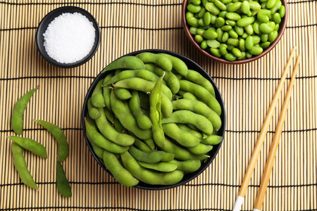 Raw green edamame soybeans and pods on wicker mat, flat layの写真素材