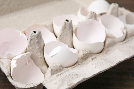 Broken eggshells in carton on table, closeup