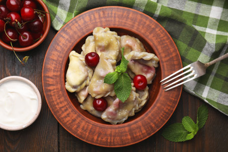 Traditional Ukrainian dumplings (varenyky) with cherries served on wooden table, flat layの写真素材