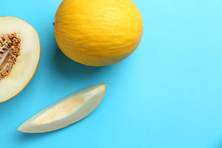 Whole and cut melons on light blue background, flat lay. Space for textの写真素材