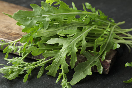 Fresh green arugula leaves on grey textured table, closeup