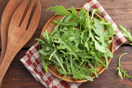 Fresh green arugula leaves and cutlery on wooden table, flat layの写真素材