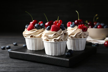 Tasty cupcakes with different berries on black wooden table, closeupの写真素材