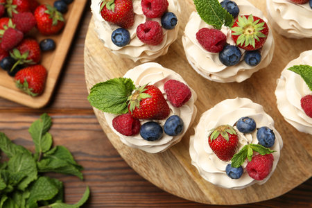 Tasty cupcakes with different berries and mint on wooden table, flat layの写真素材