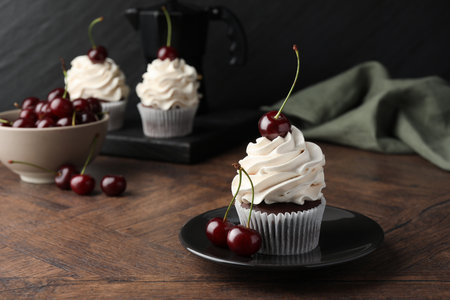Delicious cupcakes with cream and cherries on wooden tableの写真素材