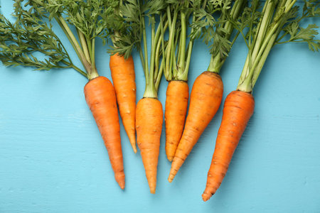 Tasty ripe juicy carrots on light blue wooden table, flat layの写真素材