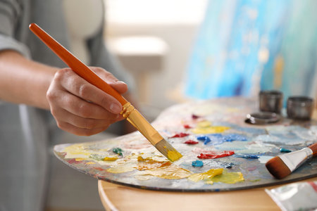 Woman with brush using palette at table indoors, closeupの写真素材