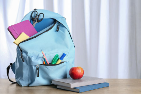 Backpack with different school stationery and apple y on wooden tableの写真素材