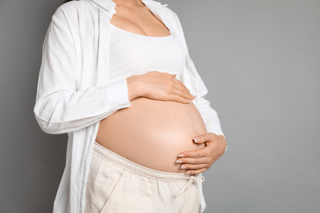 Young pregnant woman on gray background, closeup. Space for textの写真素材