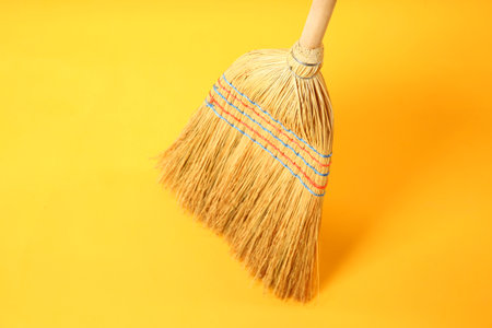 One corn straw broom on yellow backgroundの写真素材
