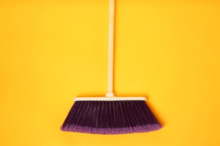 One cleaning broom on orange background, top viewの写真素材