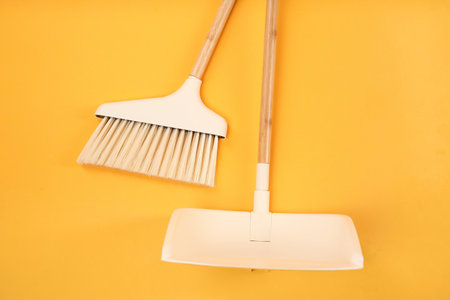 Cleaning broom and dustpan on orange background, flat lay