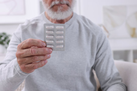 Senior man holding blister with pills at home, closeupの写真素材