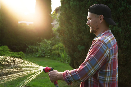 Man watering lawn with hose in backyardの写真素材