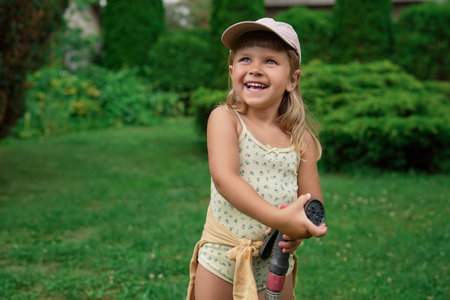 Cute little girl with hose in backyardの写真素材