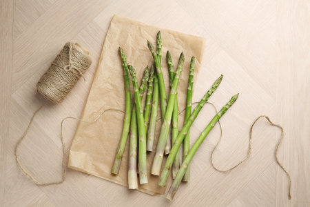 Fresh green asparagus stems and thread on wooden table, flat layの写真素材