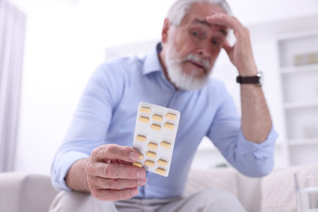 Senior man with pills at home, selective focusの写真素材