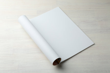 Open magazine with blank page on light wooden table. Mockup for designの写真素材