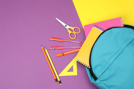 Flat lay composition with backpack and different school stationery on color background, space for...