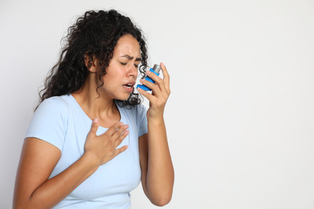 Young woman using asthma inhaler on white background. Space for textの写真素材