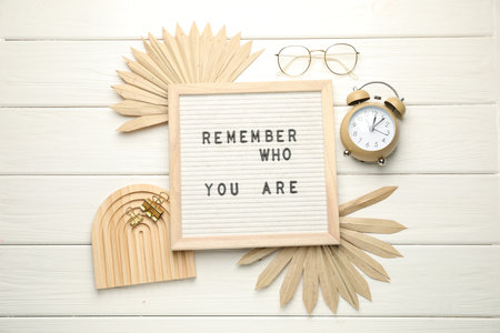 Flat lay composition of letter board with phrase Remember Who You Are on white wooden tableの写真素材